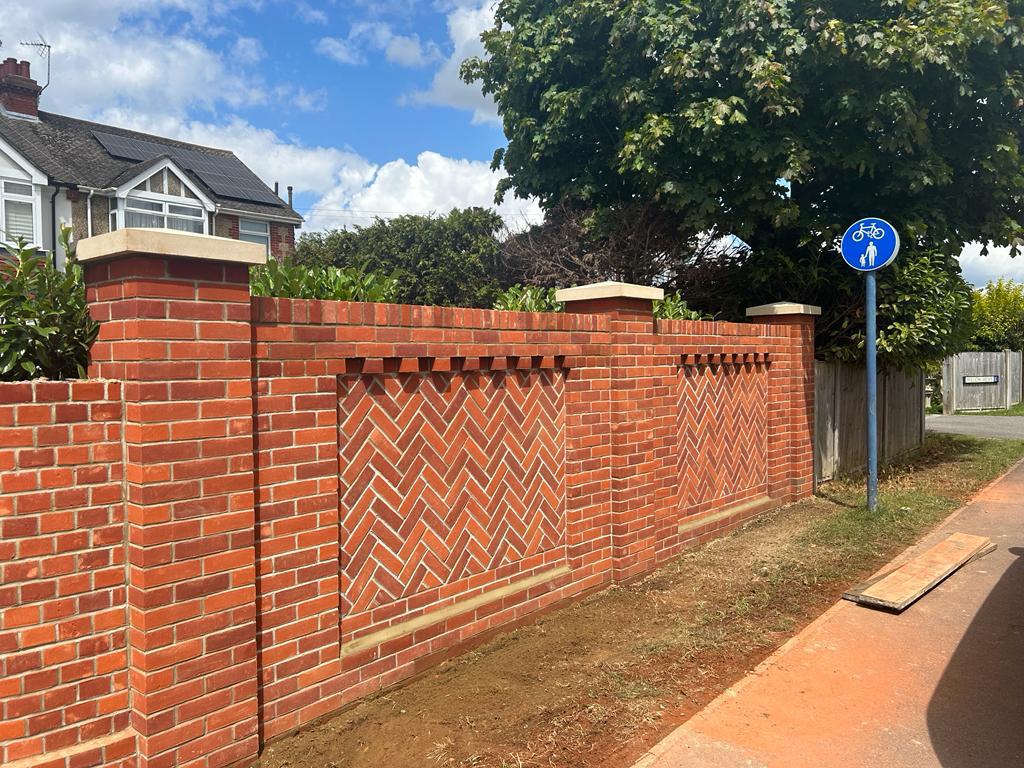 Decorative herringbone brickwork panels on a GoulPar boundary wall — craftsmanship at scale